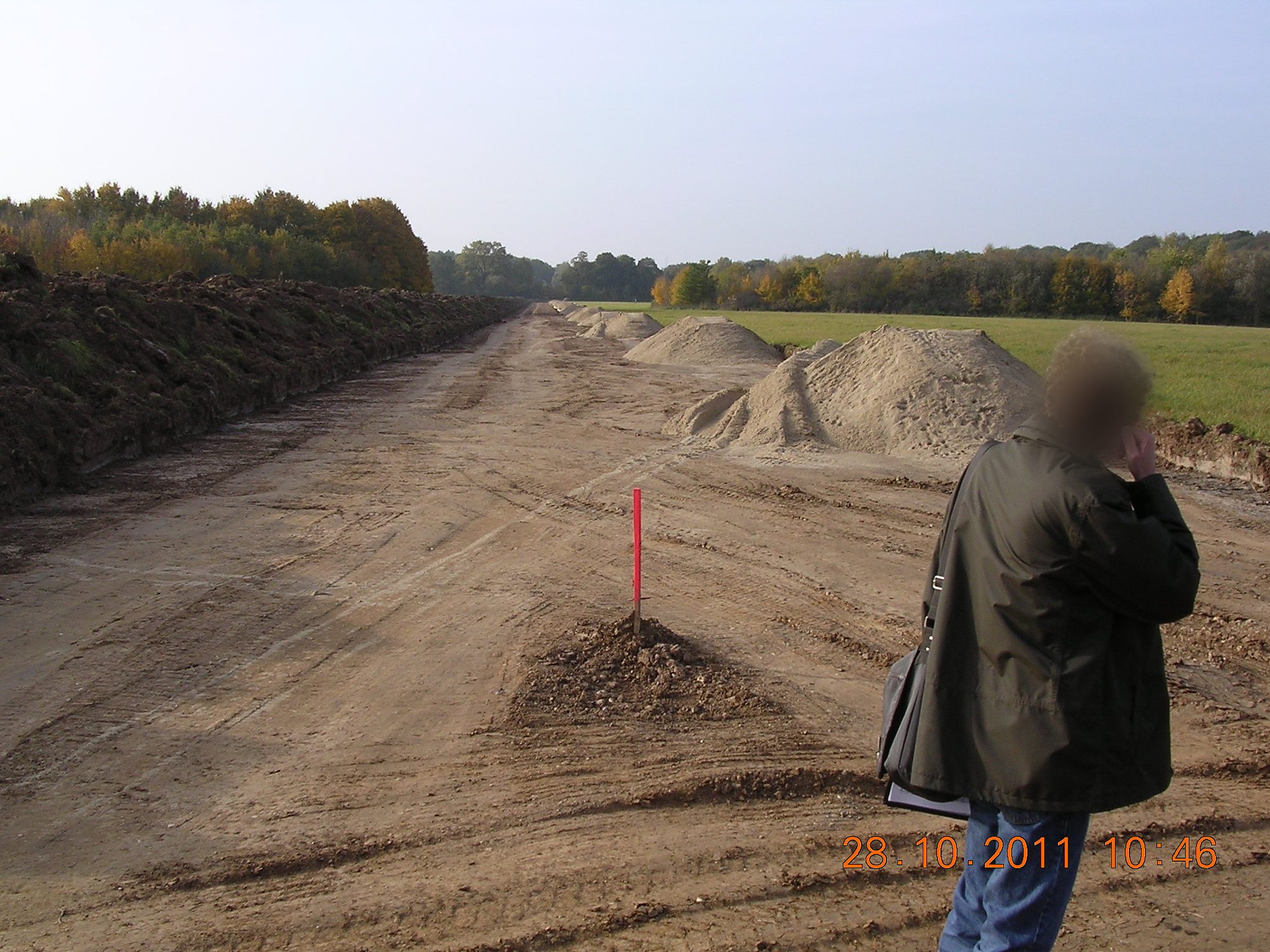 Erdarbeiten im Trassenbau einer Gasleitung mit Vermessungspunkt